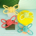 Dog playing with braided rope ball chew toy indoors interactive training