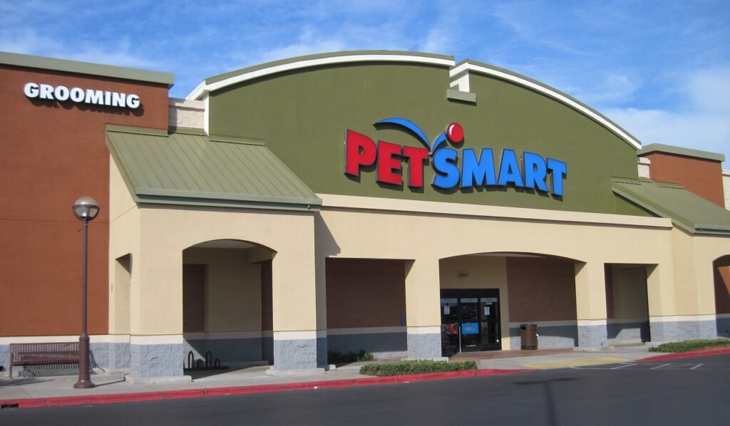 Front entrance of a PetSmart store with logo sign above the doors, representing the brand’s growth from a small pet shop to a leading pet retail empire.