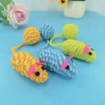 Cat playing with colorful woven mouse toy with tail ball"